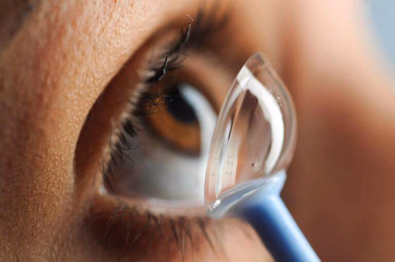 Scleral contact lens held between fingers showing its large diameter